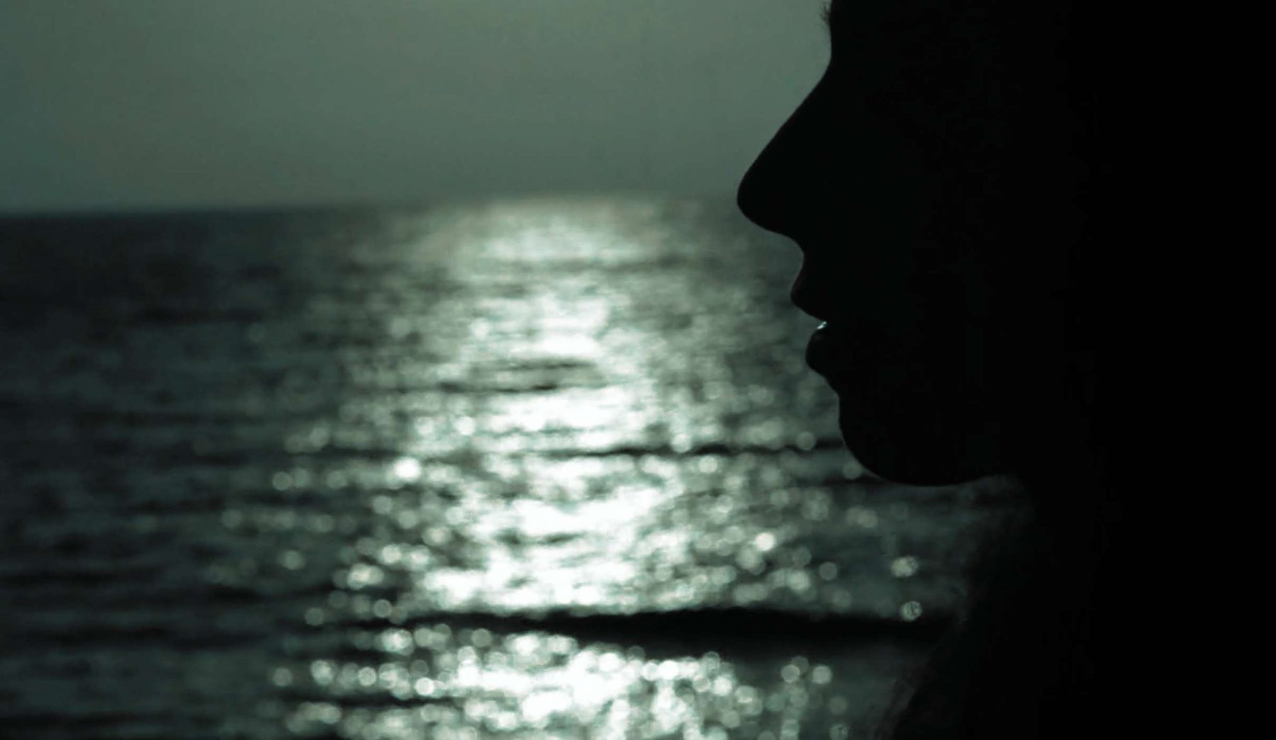 Sara in silhouette against light on the sea