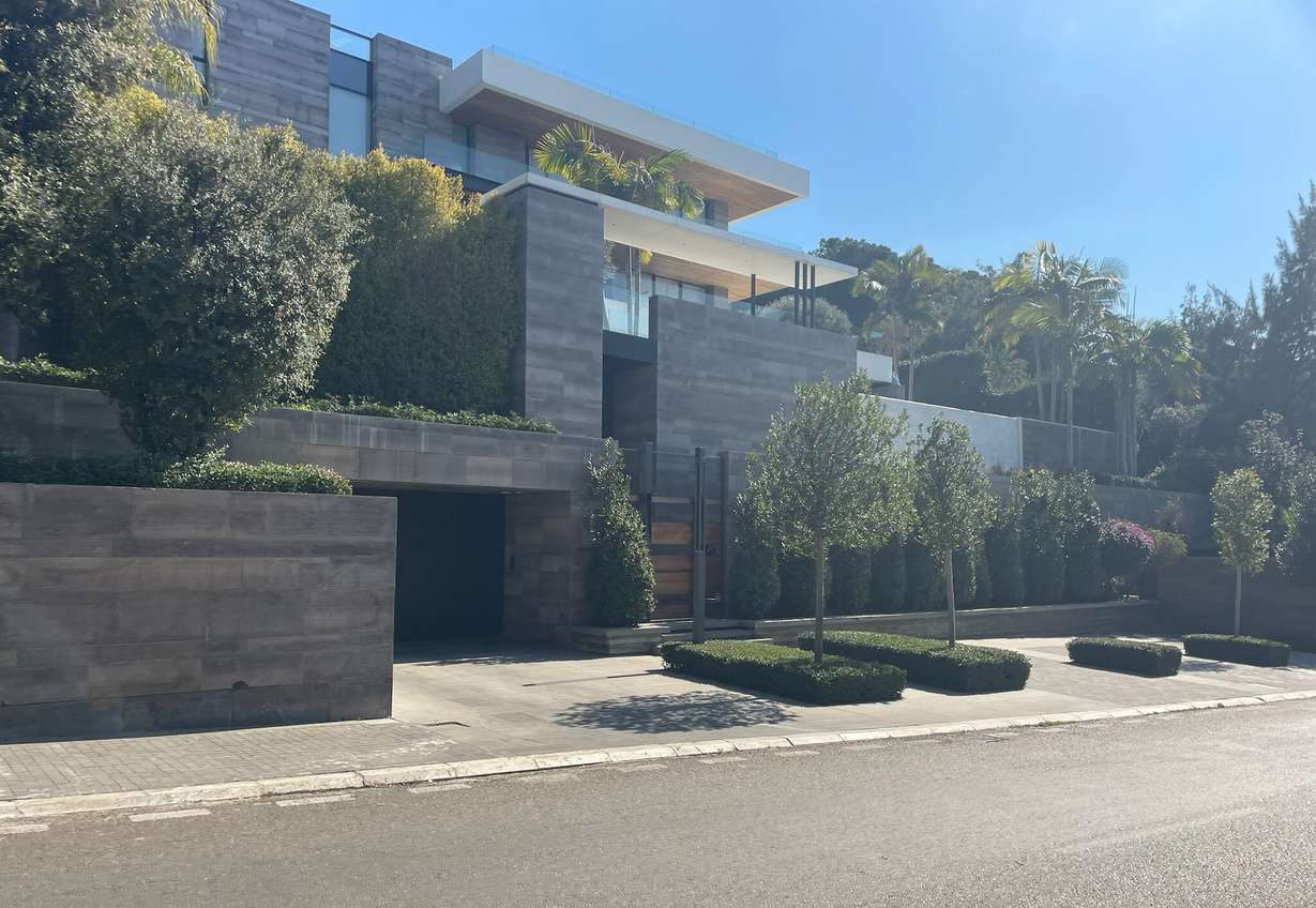 A modern mansion behind a stone wall